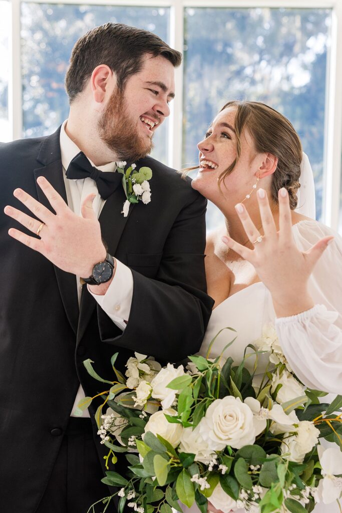 bride and groom joyfully showing off their wedding rings