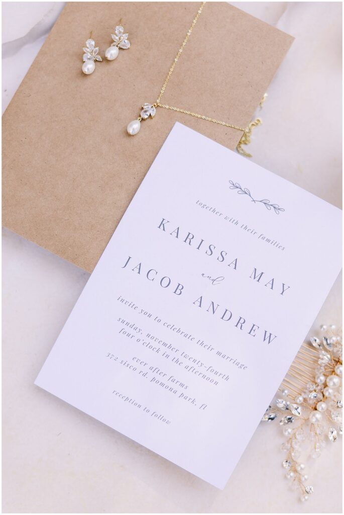 Wedding flatlay featuring the invitation suite with bridal jewlery
