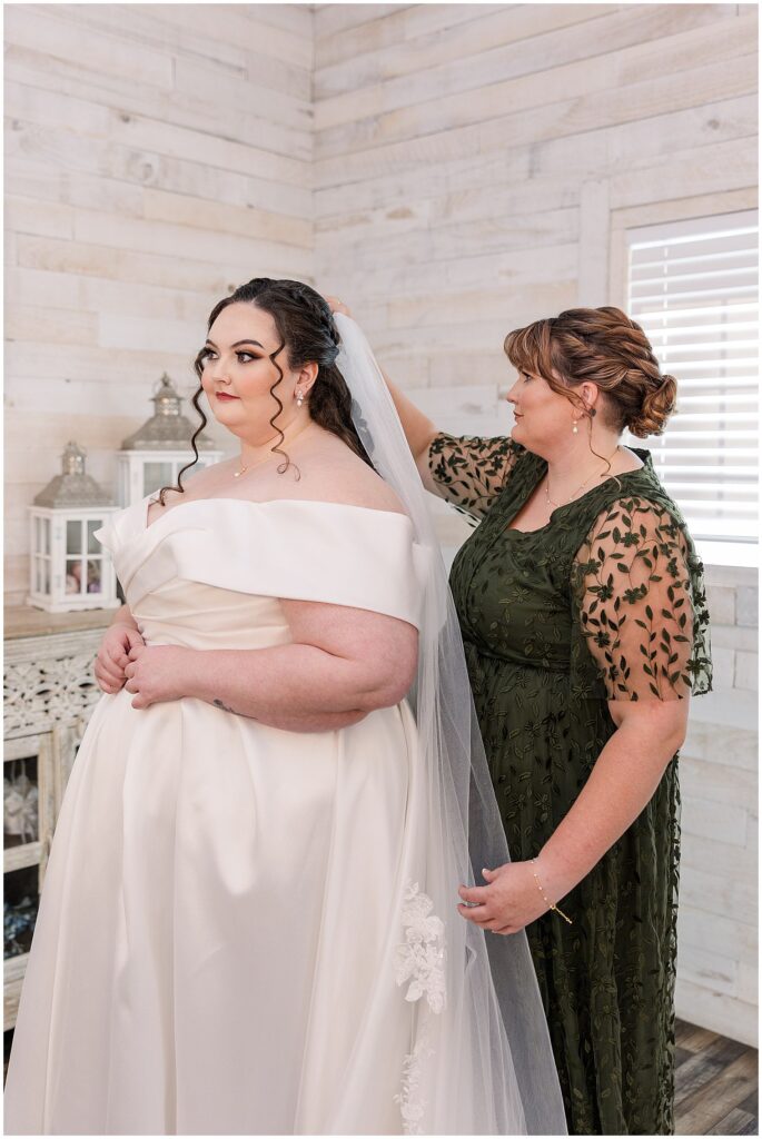 Sister putting veil on bride as they get ready