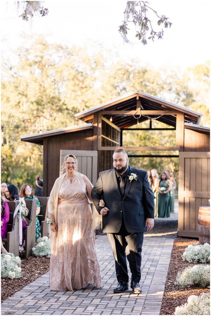 Groom entering ceremony with brides mom