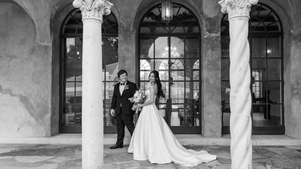 Bride and groom posing under elegant arches at an Howey Mansion Wedding Venue, captured in a timeless black and white wedding portrait